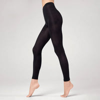 A person stands on tiptoe against a plain, light background wearing BUTIK KUBIK Sneaky fox black footless nylonstrumpbyxor.