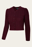 The Emmy - The Ice Skater cardigan in black cherry by BUTIK KUBIK is a maroon, long-sleeve, cropped cardigan featuring a vintage-inspired cable knit with subtle Celtic braid patterns. Crafted from extrafine merino wool, it showcases a V-neckline and front button closure, displayed against a plain background.