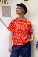 A woman stands confidently in the Kubik blouse by BUTIK KUBIK, styled with a hat and featuring oversized, vintage-inspired buttons.