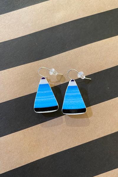 Saved & remade earrings by BUTIK KUBIK: Triangular dangle earrings in gradient blue shades with black tips, crafted from återbrukat porslin. Displayed on a tan and black striped surface.