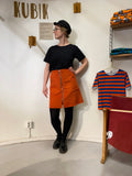 A woman stands in a room wearing the Kubik corduroy zip skirt nr 2 by BUTIK KUBIK, made from Oeko-Tex certified cotton corduroy.
