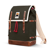 The BUTIK KUBIK YKRA Matra (green) is a vintage-inspired backpack crafted from dark green cotton canvas with brown leather straps, cream trim, a red drawstring, a mountain logo patch on the flap, and a reinforced brown leather base.
