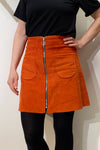 A woman wearing the Kubik corduroy zip skirt nr 1 by BUTIK KUBIK—an A-linjeformad orange kjol i bomullsmanchester.