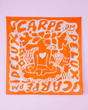 A Tropical Scandinavia scarf Carpe DM by BUTIK KUBIK, in orange and white, features a stylized figure with a heart chest among ice cream cones and bold CARPE DM text—like Lucky Charms for your wardrobe.