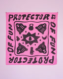 The Tropical Scandinavia scarf The Protector pink by BUTIK KUBIK features bold black motifs—eye, tigers, hand, moon, and kettlebells—on pink organic cotton, with "PROTECTOR OF FUN" repeated along its wavy border.