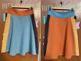 Side-by-side comparison of two flared BUTIK KUBIK Kubik skirt Twist short waffle multicolour skirts, both in size M; one with orange, yellow, teal, and black, the other a twist version with similar shades.