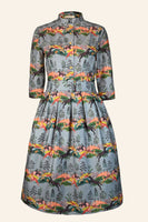 The BUTIK KUBIK Palava Dress Cynthia leaping deer is a knee-length, long-sleeved vintage-style dress with a fitted waist, high collar, and a colorful leaping deer print on a light blue background.