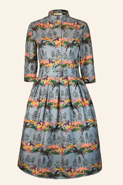 The BUTIK KUBIK Palava Dress Cynthia leaping deer is a knee-length, long-sleeved vintage-style dress with a fitted waist, high collar, and a colorful leaping deer print on a light blue background.