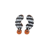 The Törmi papu mini earrings by BUTIK KUBIK are crafted from Finnish Birch plywood, featuring a curved black and white pattern with small wooden circular accents at the bottom. They arrive in eco-friendly packaging.