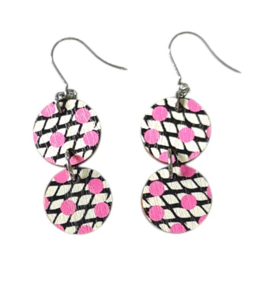 The Törmi Satu earrings pink by BUTIK KUBIK are eco-friendly dangle earrings made from Finnish birch plywood, featuring two circular discs with black and white stripes accented by pink polka dots on a white background.