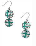 The Törmi Satu earrings by BUTIK KUBIK are lightweight dangle earrings made from Finnish birch plywood, featuring two round discs with a turquoise and white domino-inspired pattern, linked by metal rings and finished with fishhook ear wires.