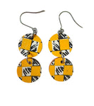 The Törmi Satu earrings yellow by BUTIK KUBIK are eco-friendly Finnish birch plywood dangles with two round discs each, featuring yellow and black checkered patterns and zebra stripes on white, connected vertically with durable metal hooks.