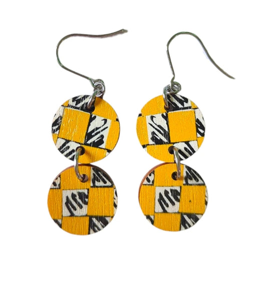 The Törmi Satu earrings yellow by BUTIK KUBIK are eco-friendly Finnish birch plywood dangles with two round discs each, featuring yellow and black checkered patterns and zebra stripes on white, connected vertically with durable metal hooks.