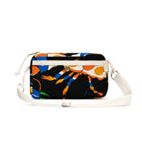 The YKRA travel MAGIC SEALIFE by BUTIK KUBIK is a small rectangular crossbody bag with a vibrant abstract crab design in orange, blue, and white on black. It has a white adjustable strap, gold button on the front pocket, and includes an essentials organizer for modern travelers.