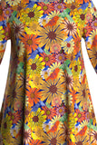 The Cissi och Selma dress Anita by BUTIK KUBIK is a vibrant long-sleeve tunic crafted from ekologisk bomullstrikå, featuring colorful floral patterns with yellow, orange, and white daisies on a multicolored background, enhanced with swirling details and geometric shapes.