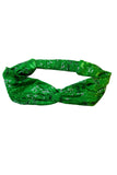 The Cissi & Selma Hedda hårband Ängsblom grön from BUTIK KUBIK is a soft viskose headband with a twisted knot, elastic back, and is decorated with white flowers and dark green leaves for a charming look.