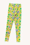 Cissi och Selma Lo Leggings Humlesurr gul by BUTIK KUBIK, made from organic cotton with a vibrant yellow floral pattern and green leaves on a yellow background, displayed on a plain white surface.