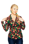 A smiling blonde woman in a side braid wears the Cissi och Selma blus Matilda Hassel Rooibos from BUTIK KUBIK with dark jeans, standing against a white background. She gently touches her braid and collar.