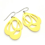 Favoretro Earrings Loops lemon haze by BUTIK KUBIK are yellow, teardrop-shaped akryl earrings with cut-out abstract designs and silver surgical steel hooks, shown on a white background.
