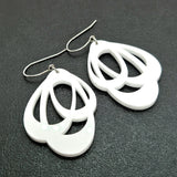 Favoretro Earrings Loops Plain White by BUTIK KUBIK: white, layered teardrop-shaped acrylic earrings with silver surgical steel hooks, shown on a textured black surface.