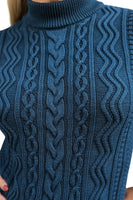 Close-up of a person wearing the Cissi och Selma tröja Signe Ocean by BUTIK KUBIK. This teal, cable-knit sweater in ekologisk bomull features intricate patterns and a high, ribbed turtleneck. Person's face is not visible.