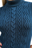 Close-up of a person wearing the Cissi och Selma tröja Signe Ocean by BUTIK KUBIK. This teal, cable-knit sweater in ekologisk bomull features intricate patterns and a high, ribbed turtleneck. Person's face is not visible.