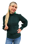 A smiling woman with long blonde hair wears the BUTIK KUBIK Cissi och Selma tröja Signe Skog, green earrings, and blue jeans, standing against a white background.