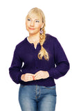 A woman with blonde hair in a side braid wears the Cissi och Selma cardigan Sigrid Lila by BUTIK KUBIK and blue jeans, standing against a white background and smiling softly while looking to the side.