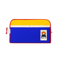 The YKRA Dopppack Triocolor by BUTIK KUBIK is a vibrant cotton canvas bag featuring a yellow top, blue bottom, and red trim. A small mountain-design patch with YKRA adds flair. A white zipper on top makes it an ideal travel companion.