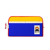 The YKRA Dopppack Triocolor by BUTIK KUBIK is a vibrant cotton canvas bag featuring a yellow top, blue bottom, and red trim. A small mountain-design patch with YKRA adds flair. A white zipper on top makes it an ideal travel companion.