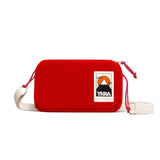 A red rectangular crossbody bag called YKRA travel Red by BUTIK KUBIK features a cream strap, pink drawstrings, and a front patch with a mountain, sun, and the text “YKRA”—making this stylish compact organizer the perfect travel accessory for your next adventure.