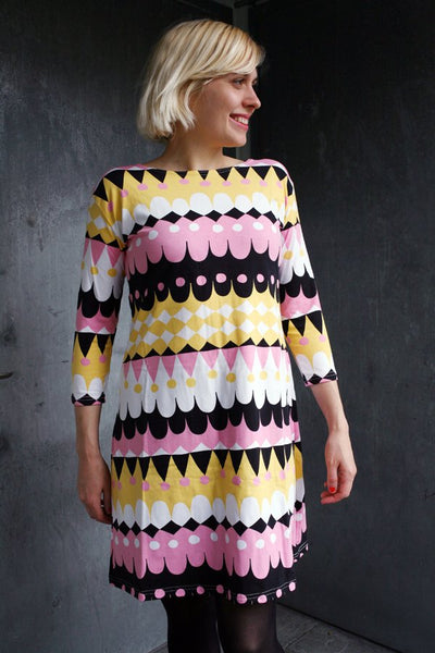 A-linjeformad klänning med tryck i vitt, rosa, ljusgult och svart. 60-talsinspirerad med trekvartsärm.