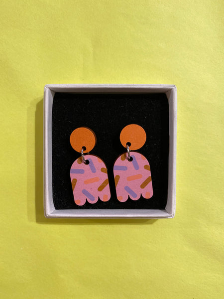 Törmi Nonparelli earrings pink by BUTIK KUBIK: Colorful Finnish birch plywood earrings with round orange tops, pink abstract shapes, and purple-orange patterns on yellow, presented in a white box with black interior.
