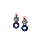 Törmi herkku earrings by BUTIK KUBIK are dangle earrings crafted from Finnish birch plywood, with three stacked circles: a pink disc, a black-and-white netted circle, and a textured dark blue hollow circle.