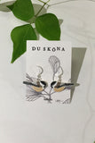 Two handpainted Du sköna bird earrings Talltita with willow tit motifs and sterling silver hooks on a BUTIK KUBIK branded display card.